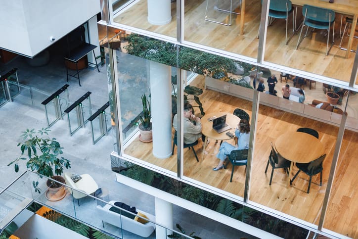 Highrise building with clear glass showing people working at desks